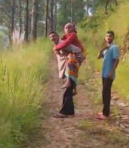 सड़क क्षतिग्रस्त होने से बुजुर्ग महिला को कंधे पर लादकर ग्रामीणों ने पहुंचाया अस्पताल